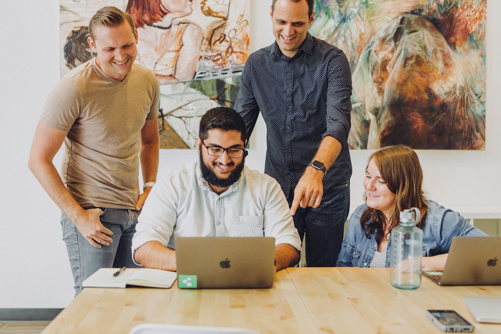 Colleagues collaborating around a laptop